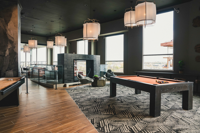 Apartment amenity clubroom and dining area with wood-slat ceiling detail and pendant lighting