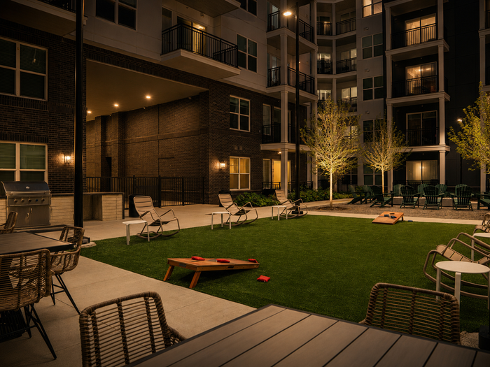 Apartment community pool deck with shade umbrellas and site lighting along the surrounding grounds