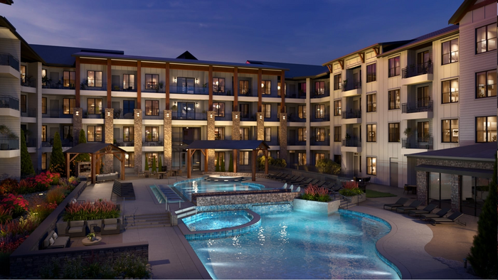 Four-story apartment building exterior above a pool deck, showing building-mounted exterior lighting